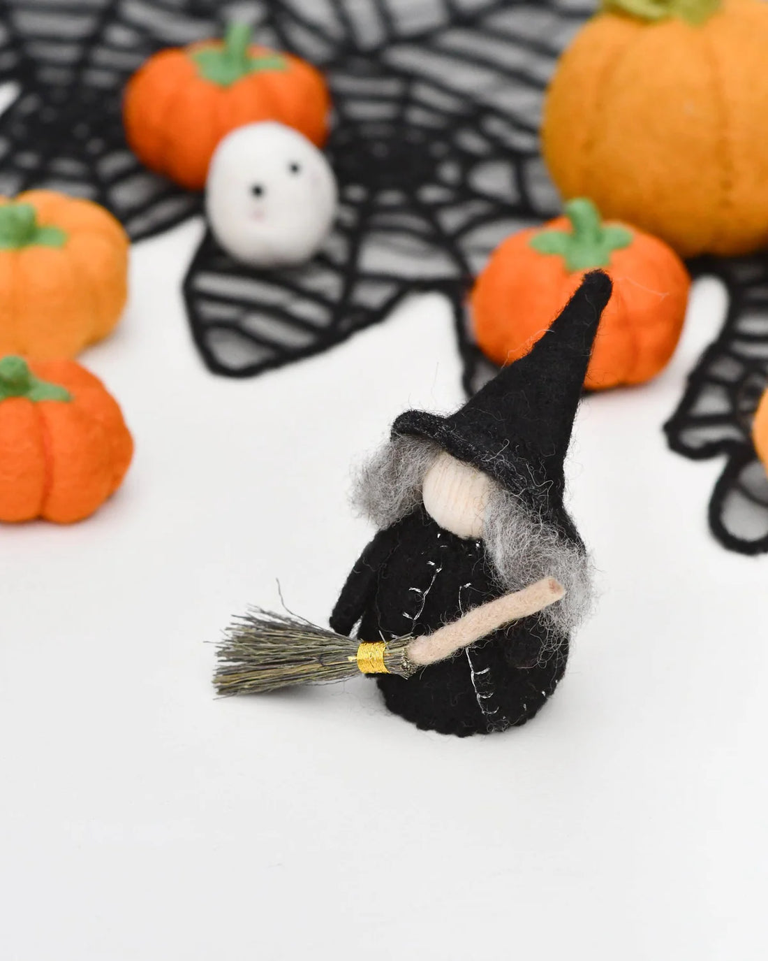 Felt peg doll witch in a long cloak on a silver birch body, holding a broom