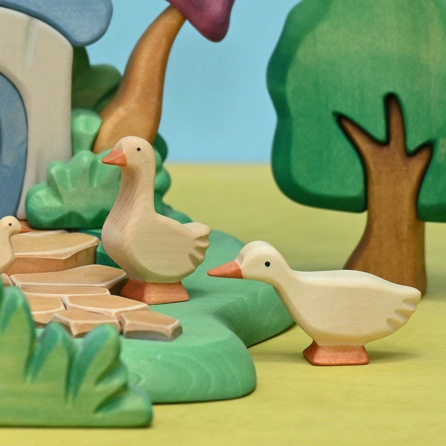 Wooden goose with head up set beside a wooden pond scene