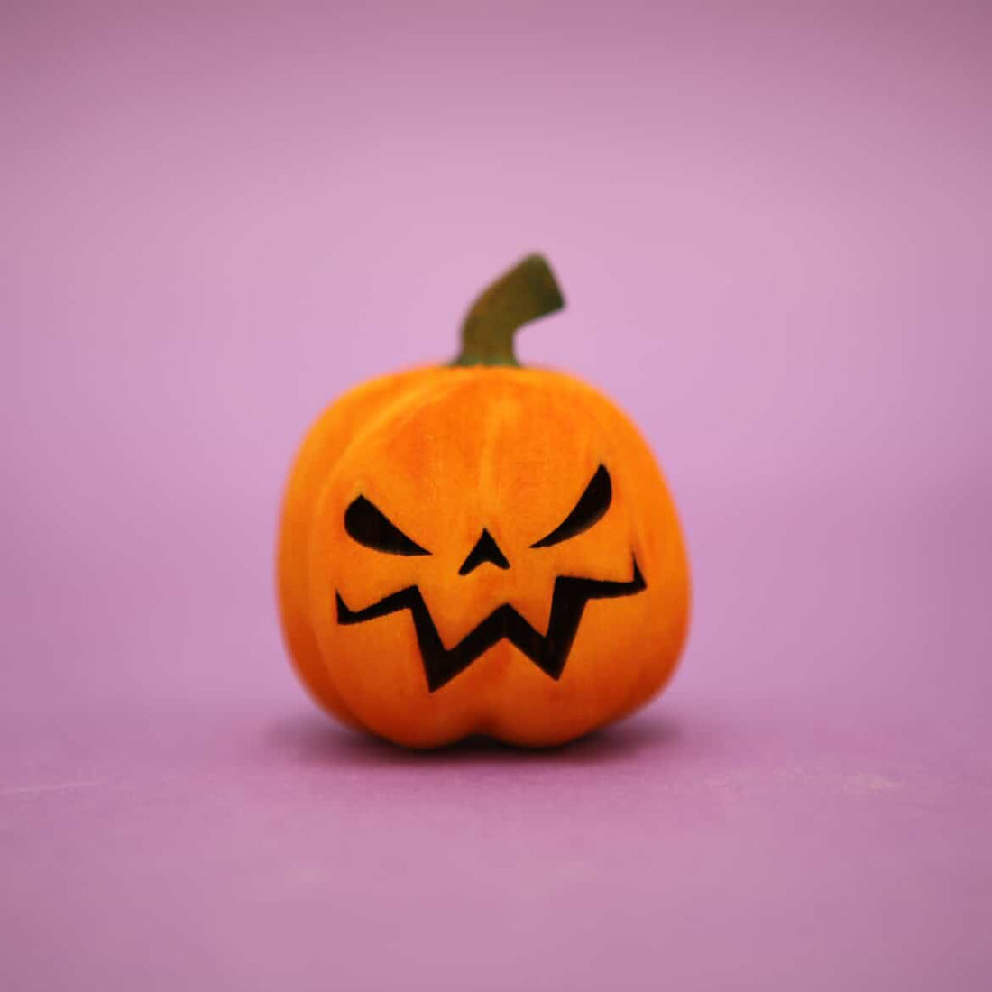 Wooden carved pumpkin with black triangle eyes and a jagged grin