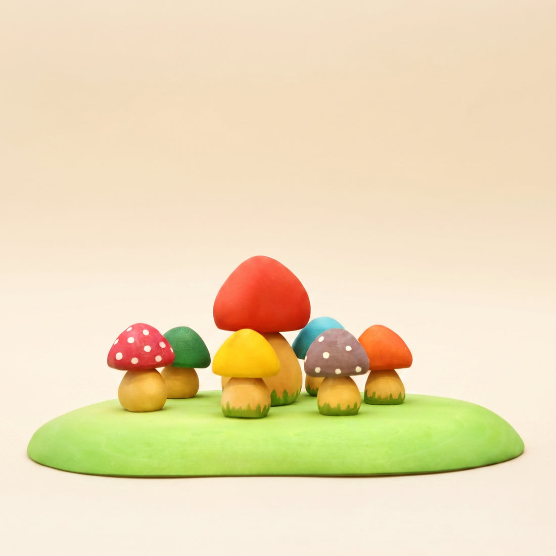 Set of small wooden mushrooms in red, yellow, and orange on a green base