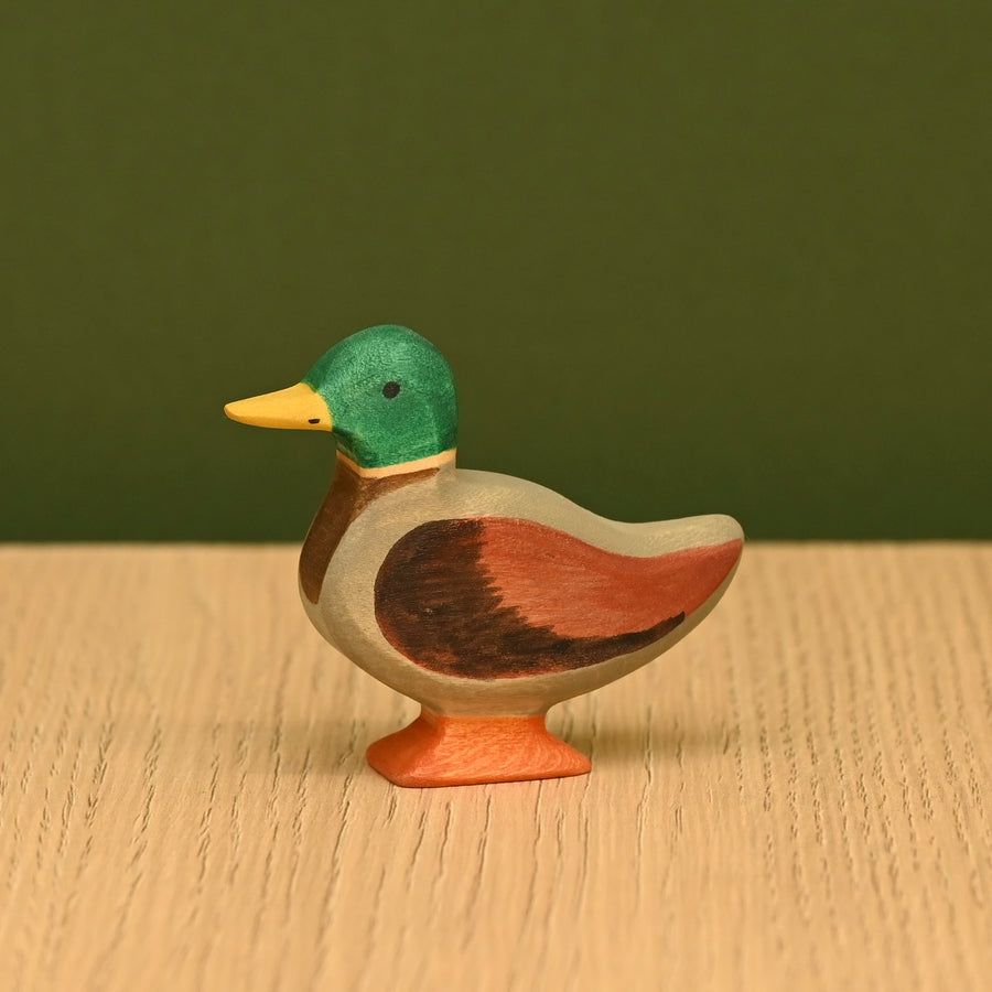 Wooden mallard duck on a wood surface, showing the carved body and painted wing detail