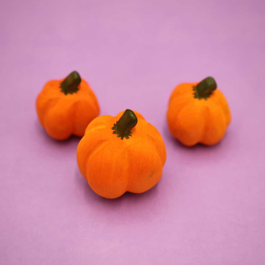 Three plain wooden pumpkins with carved ribs and dark stems