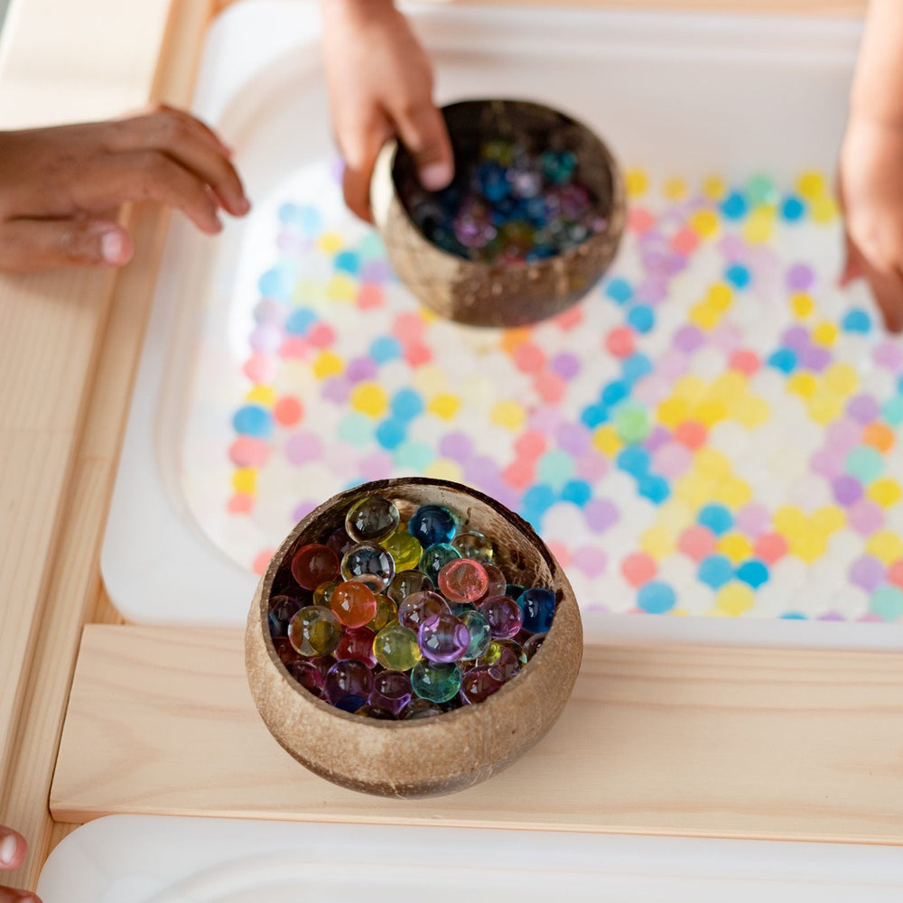 Q Toys patterned coconut rice bowls holding colored water beads on a sensory tray