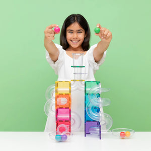 A child holding two wooden balls above a finished Bright ball run