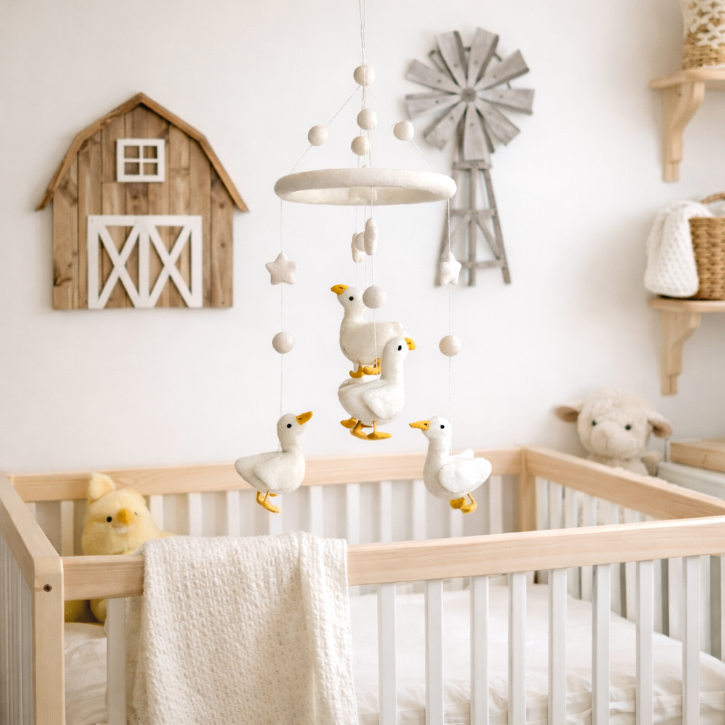 Handmade felt baby mobile with a white duck and pastel clouds hanging above a crib