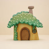 Wooden dwarf's house with a mossy green roof, white flowers, a rounded door, and a chimney · view 1