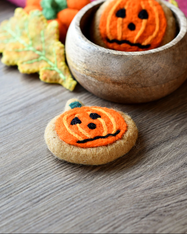 Round orange felt cookie with a frazzled pumpkin face needle-felted into the surface