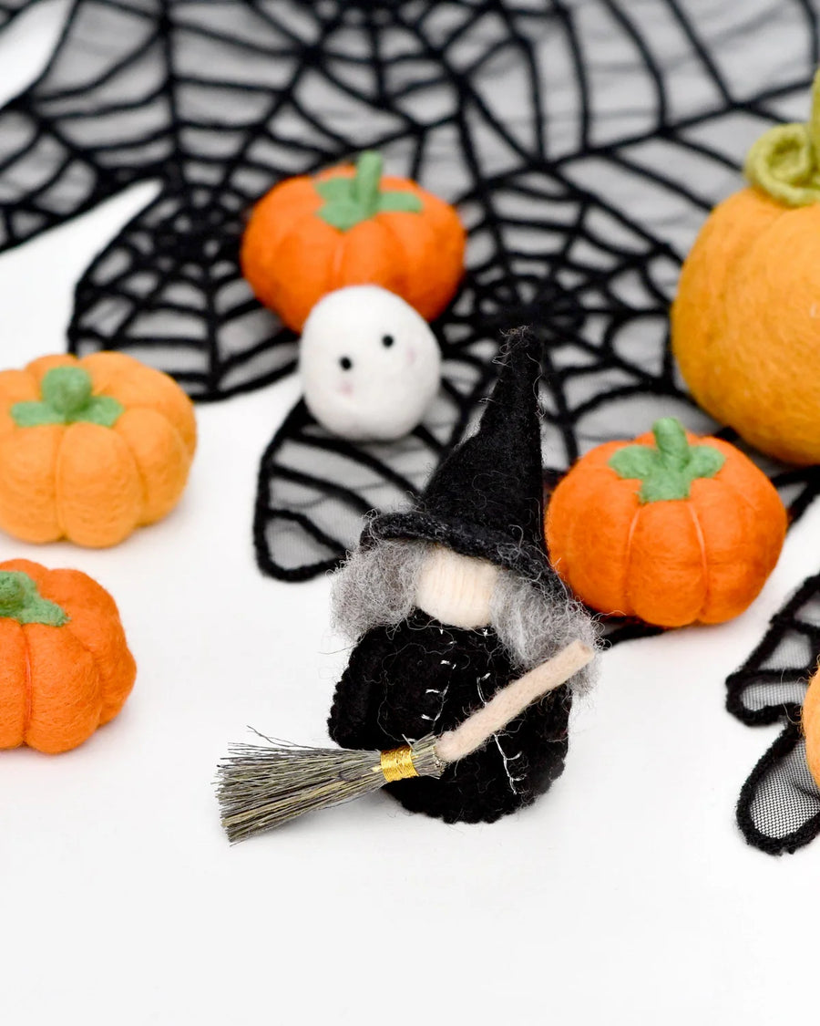 Cloaked felt witch peg doll standing beside other Halloween pieces
