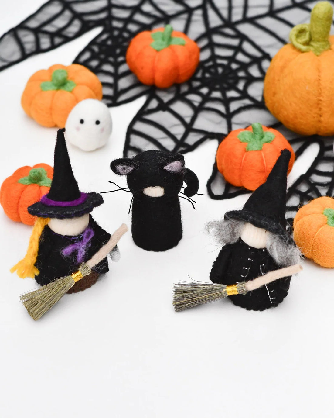 Felt peg doll witch in a pointed hat on a silver birch body, holding a broom