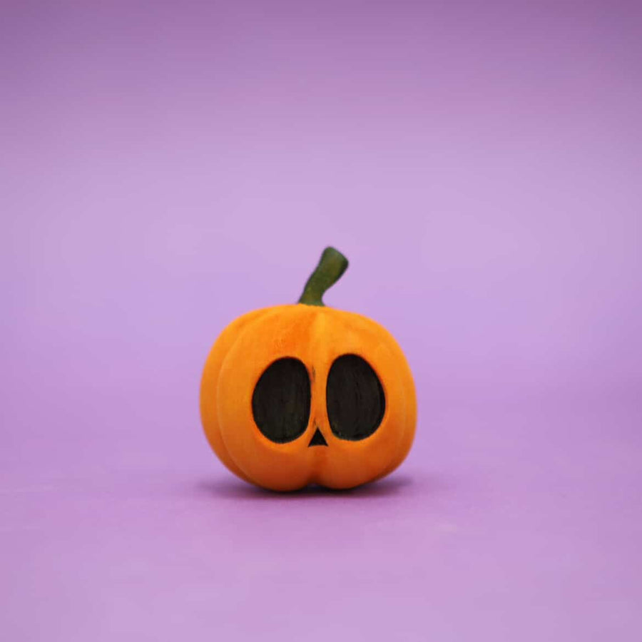 Wooden carved pumpkin with two wide oval eyes and a small triangle nose