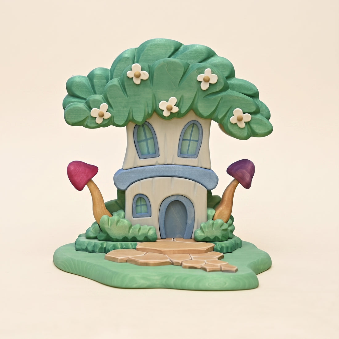 Wooden fairy house grown into a flowering tree, on a carved base with a stone path and toadstools