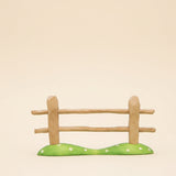 Wooden fence section with two rails on a green painted base · view 1