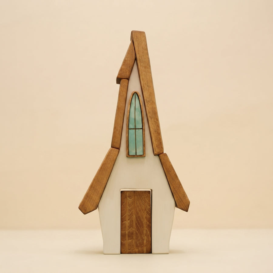Wooden house with a steep roof, a tall arched window, and a door that lifts out