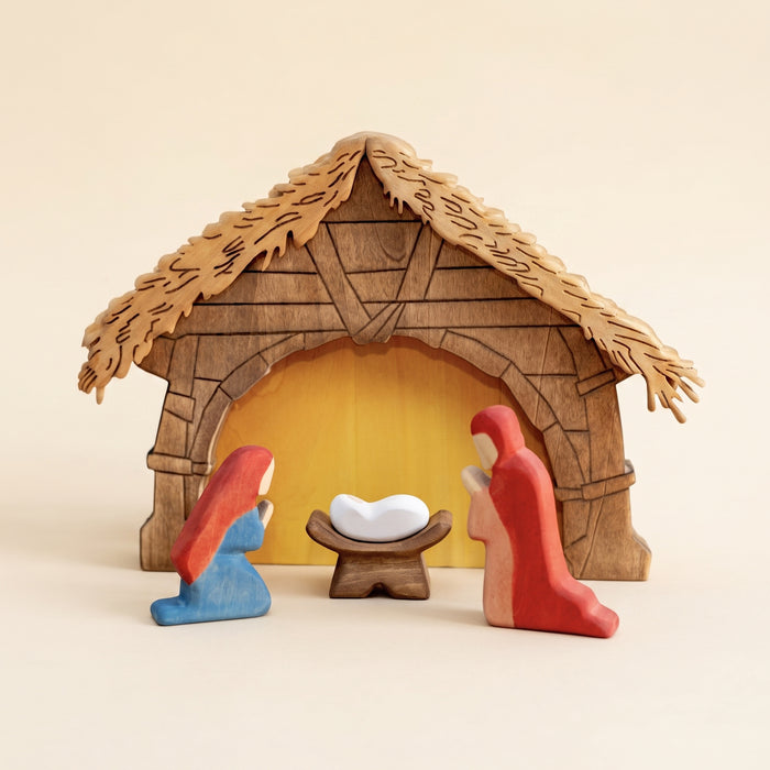 Wooden nativity scene in a thatched stable with the holy family inside