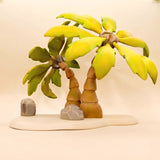 Two wooden palm trees on a shared sand-coloured base, trunks ringed like palm bark, broad yellow-green fronds · view 1