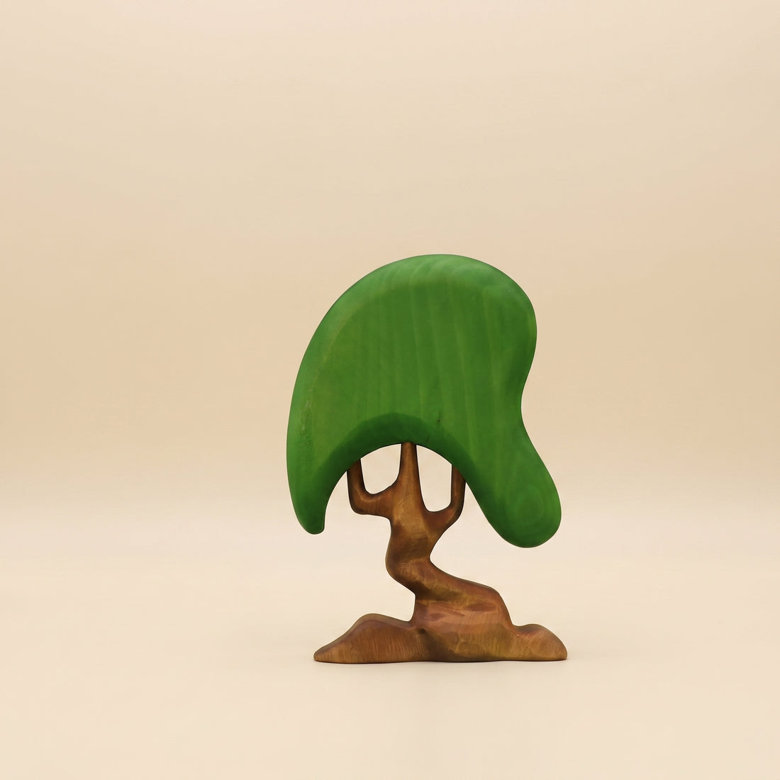 Wooden tree with a broad green canopy on a twisting brown trunk that splits low