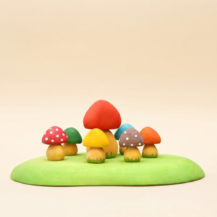 Set of small wooden mushrooms in red, yellow, and orange on a green base
