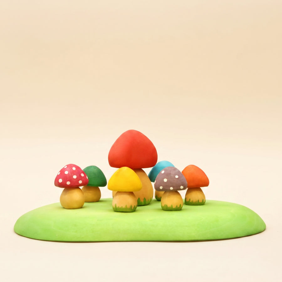 Set of small wooden mushrooms in red, yellow, and orange on a green base