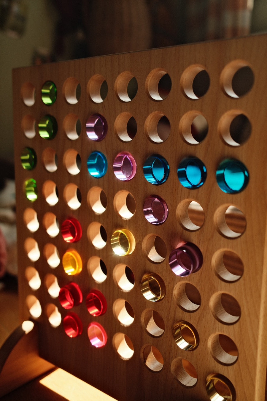 Colored Bauspiel lucent cylinders set in the holes of the wooden game board