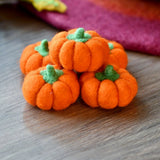 Second view of the bright orange felt pumpkins showing their rounded ribbed shape · view 2