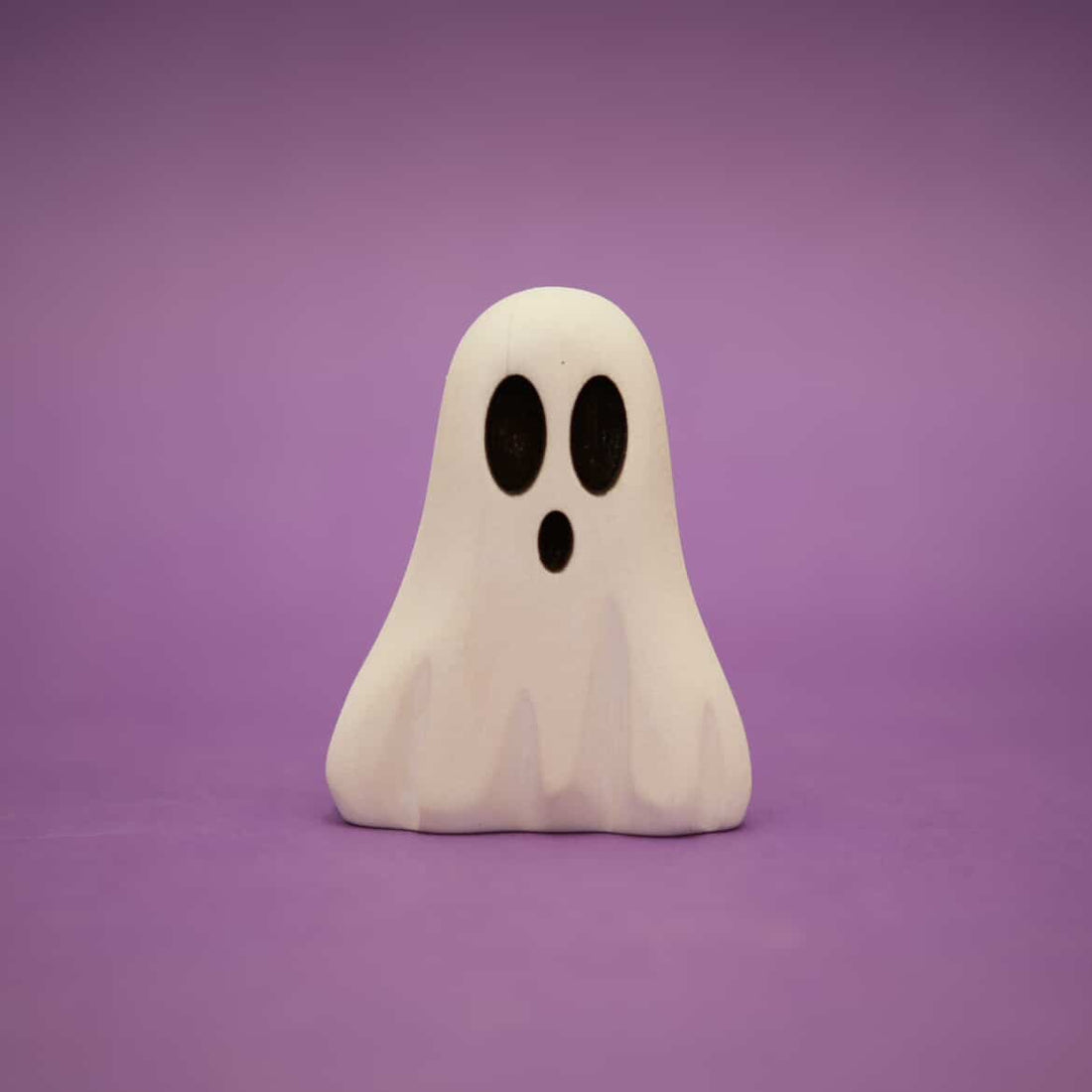 Small wooden ghost painted white with two dark oval eyes and an open mouth