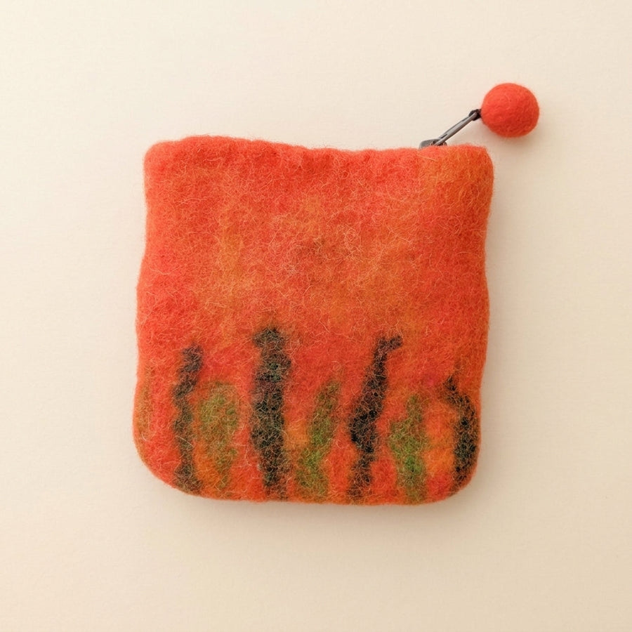 The back of the orange felt purse, with green and brown grass felted along the bottom