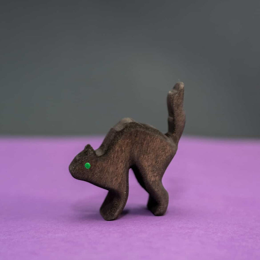Wooden black cat with an arched back and a single green eye