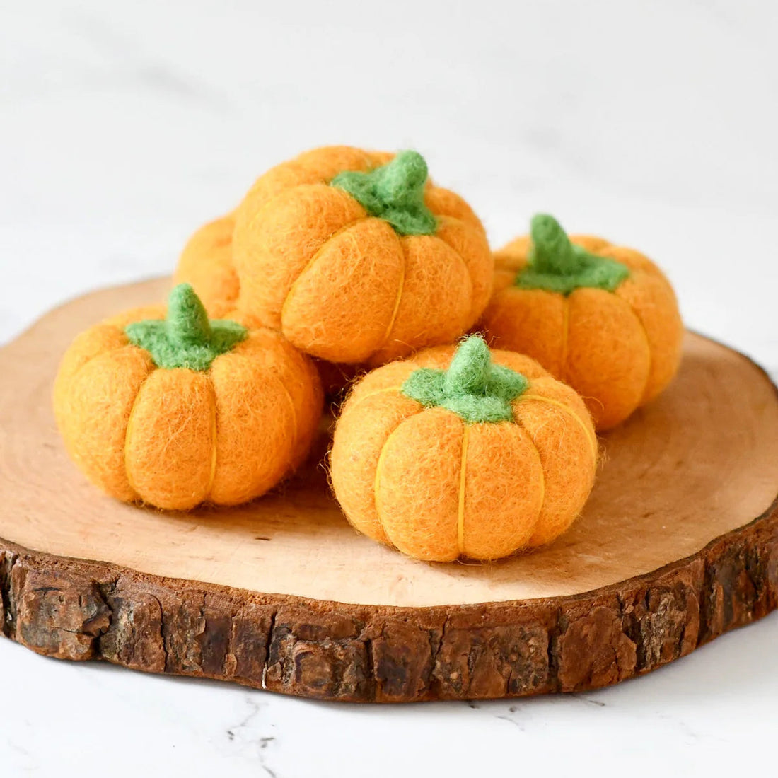 Five small felt pumpkins in deep orange, each with a stitched stem