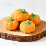 Five small felt pumpkins in deep orange, each with a stitched stem · view 1