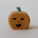 Juharka wooden pumpkin with a winking painted face and a curled green stem · view 1