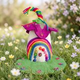 Rainbow Shimmer fairy house, a magenta-pink petal roof with a green felt swirl and a full rainbow-striped felted archway over a white doorway · view 1