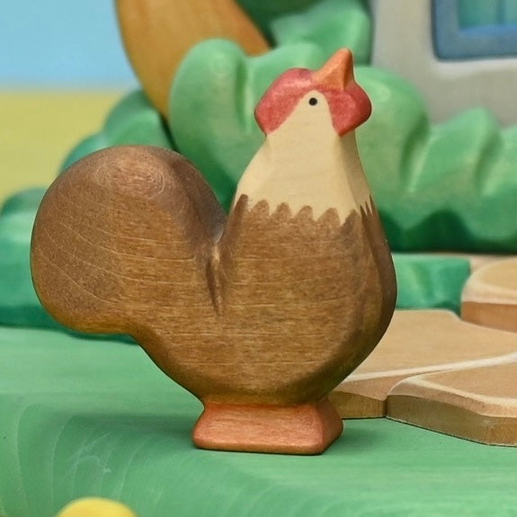 Wooden rooster set among hens and chicks in a farmyard play scene