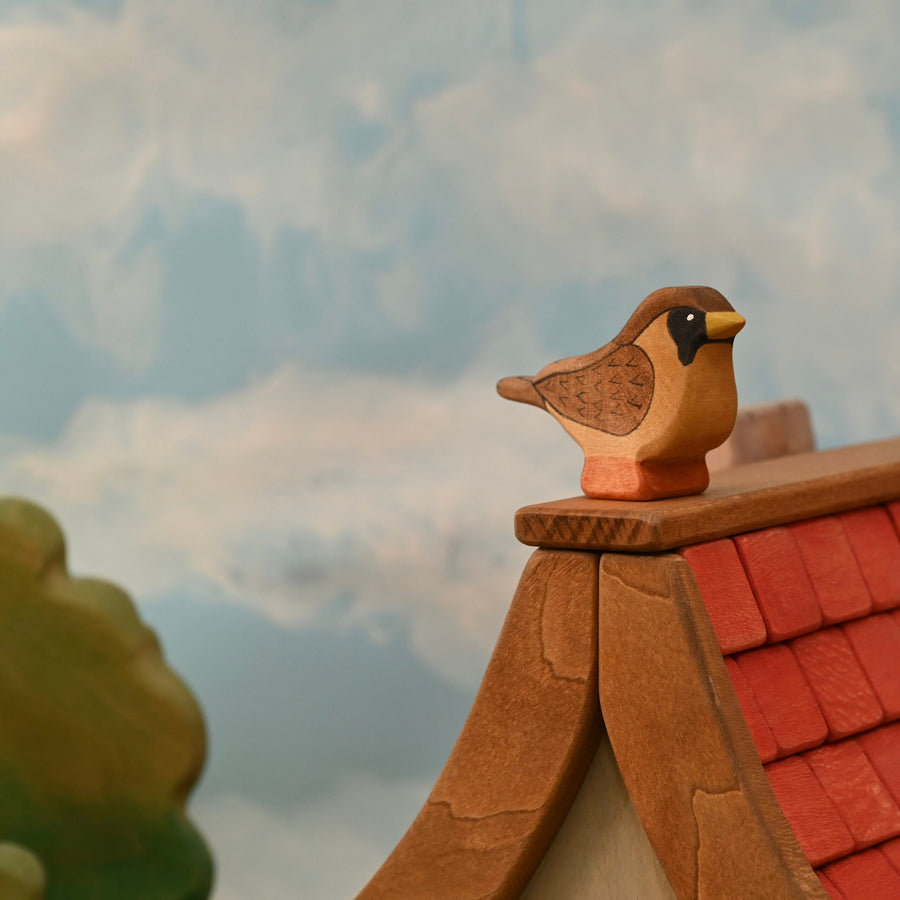Wooden sparrow figure with a black mask and painted chevron wing markings, standing on a small base