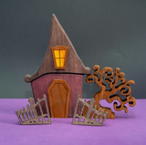Wooden Halloween witch house with a tall pointed roof, a lit lantern above the door, and a curling bare tree at its side · view 1