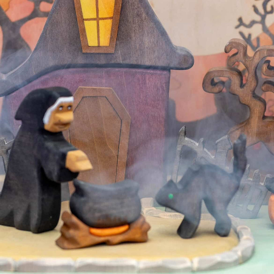 Second view of the wooden witch house set showing the fence and pumpkins in front of the house